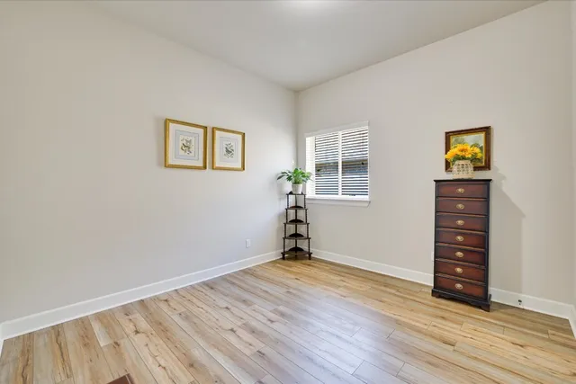 an empty room with wooden floor closet and windows