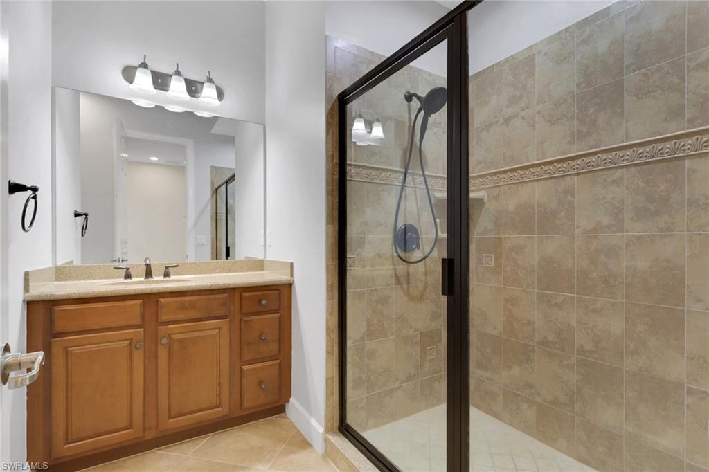 7877 Clemson Street, Unit 202 Naples, FL 34104 - Photo 24 of 36 a bathroom with a granite countertop sink a mirror and shower