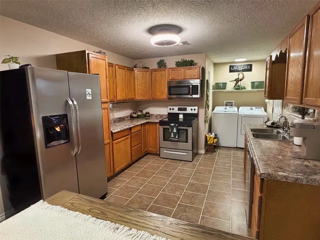 a kitchen with stainless steel appliances granite countertop a stove refrigerator sink and microwave