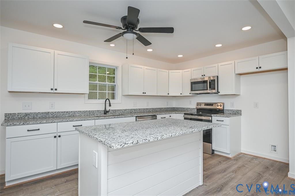 815 Kirby Street West Point, VA 23181 - Photo 7 of 29 a kitchen with stainless steel appliances granite countertop a sink a stove a refrigerator and island with wooden floor