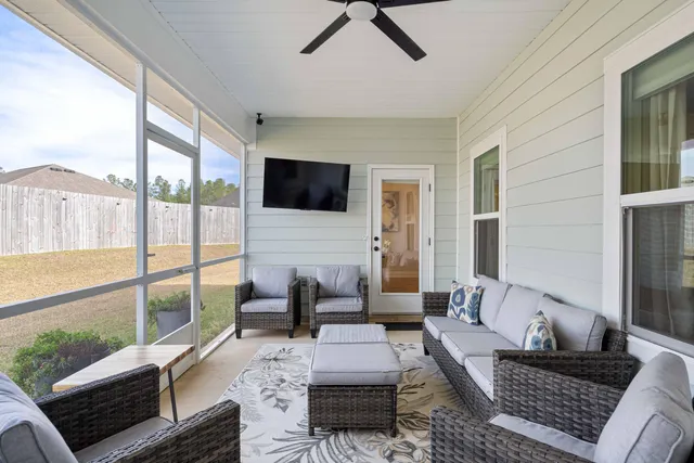 a living room with furniture floor to ceiling window and a flat screen tv