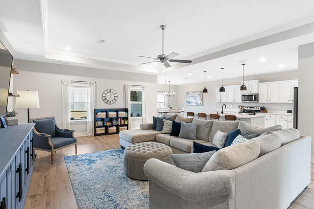 a living room with furniture kitchen view and a chandelier
