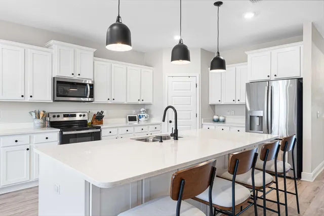 a kitchen with stainless steel appliances a stove a sink a microwave a stove a refrigerator a center island and cabinets