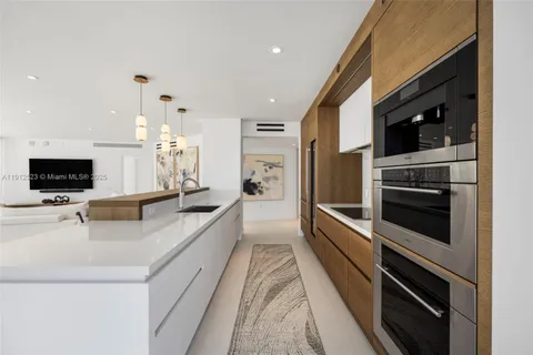 a large white kitchen with a large counter top appliances and a window