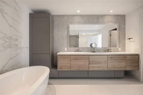 a bathroom with a double vanity sink mirror and bathtub