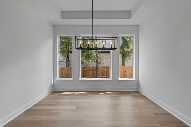 an empty room with wooden floor and chandelier