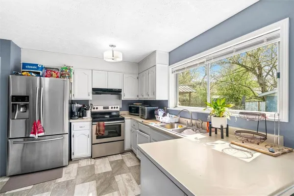 a kitchen with stainless steel appliances granite countertop a refrigerator and a sink