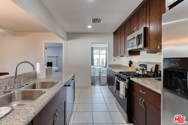 a kitchen with stainless steel appliances granite countertop a sink stove refrigerator and cabinets
