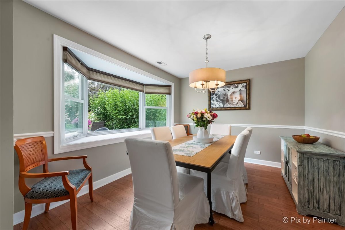 1025 Oswego Road Naperville, IL 60540 - Photo 9 of 42 a dining room with furniture a chandelier and wooden floor