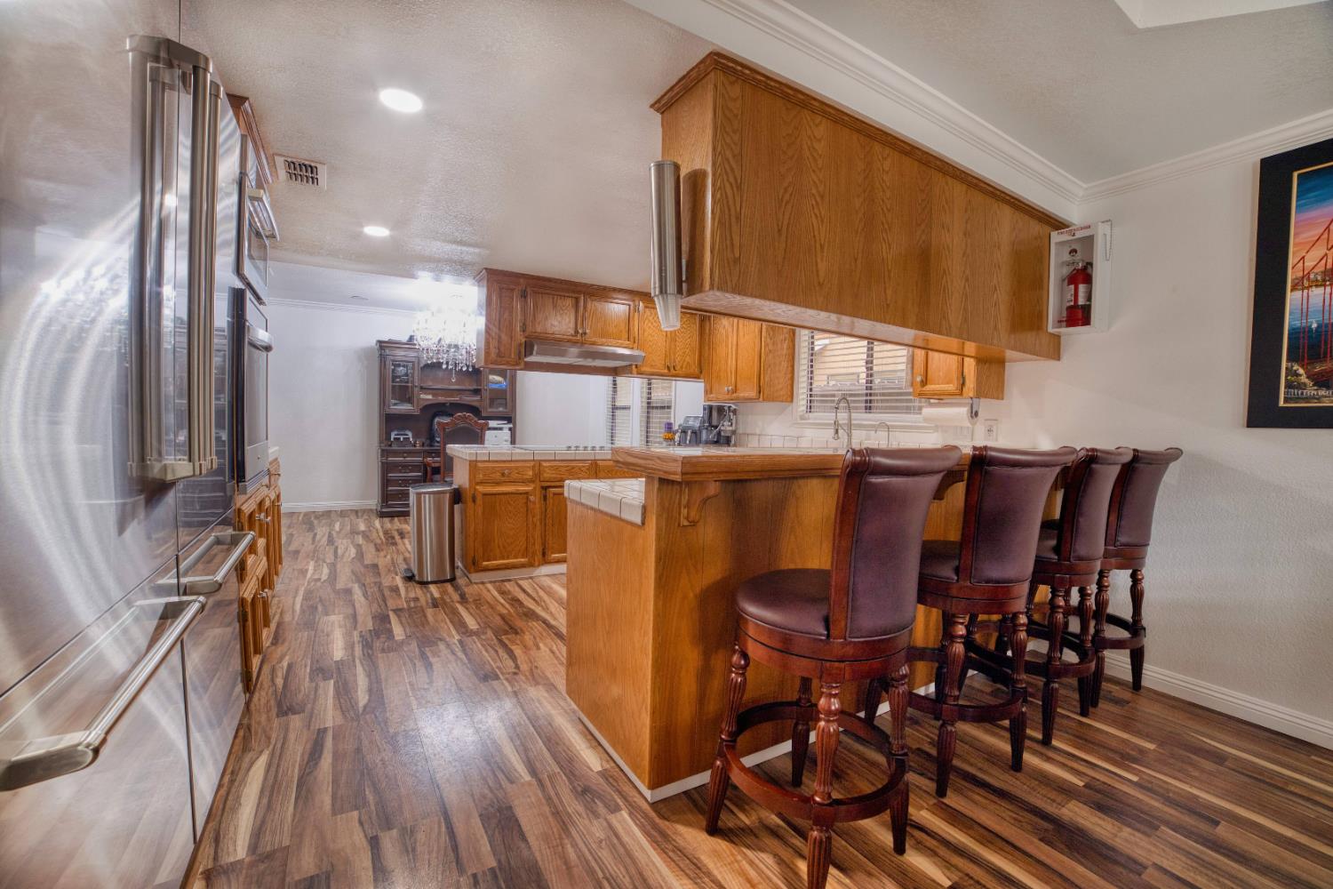 2520 Meadowrest Way Madera, CA 93637 - Photo 9 of 39 a dining room with stainless steel appliances granite countertop a refrigerator a stove a sink with island chairs and wooden floor