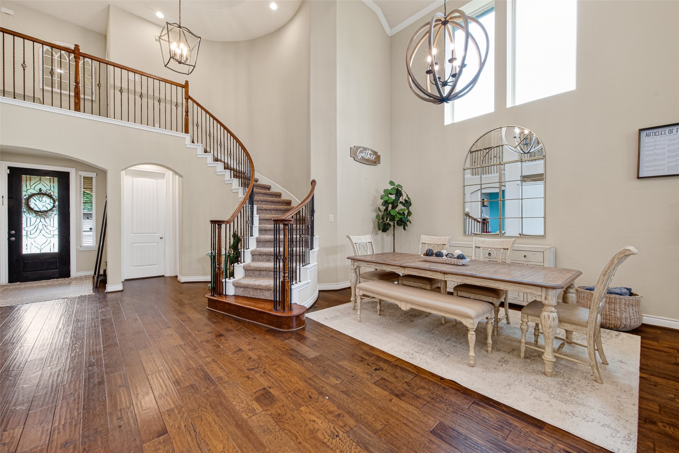 25611 Ellis Ridge Court Katy, TX 77494 - Photo 6 of 49 This inviting entryway features a grand staircase with elegant railings, high ceilings, and abundant natural light. The open dining area includes a stylish chandelier and a large mirror, enhancing the spacious feel. Dark wood floors add warmth and sophistication to the space.