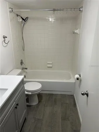 a bathroom with a granite countertop bathtub shower sink vanity and toilet