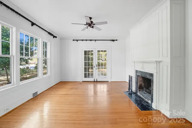 a view of an empty room with wooden floor fireplace and a window
