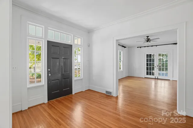 a view of an empty room with window and wooden floor