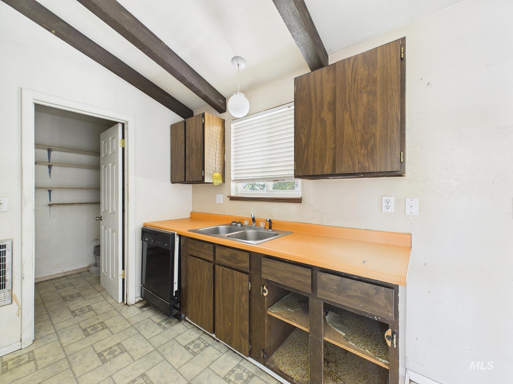 1527 North Plaza Road Emmett, ID 83617 - Photo 11 of 33 Kitchen area featuring exposed ceiling beams, wood-finish cabinetry, a double basin sink, and an integrated dishwasher