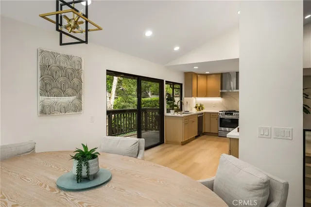 a living room with stainless steel appliances furniture a chandelier and a view of kitchen