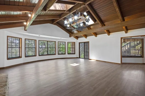 a view of an empty room with wooden floor and a ceiling fan