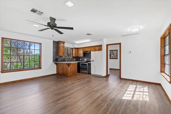 a view of kitchen with stainless steel appliances wooden floor and cabinets
