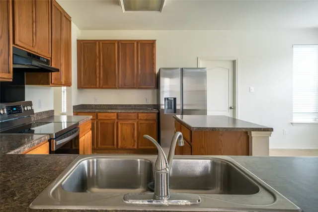 a kitchen with a sink a counter top space cabinets and stainless steel appliances