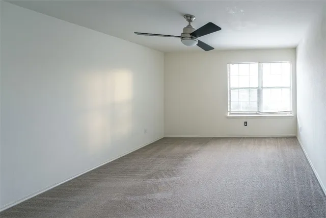 an empty room with window and ceiling fan