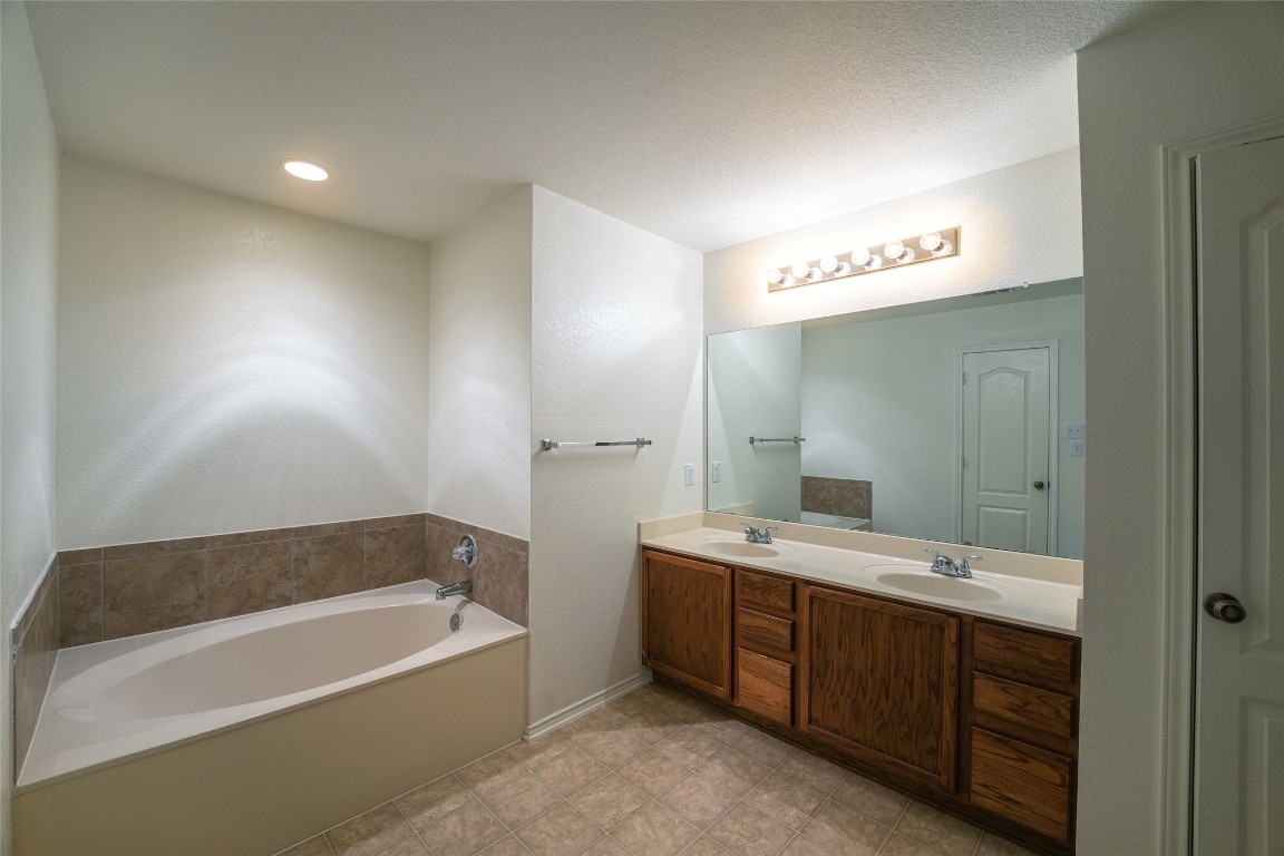 612 Dark Tree Lane Round Rock, TX 78664 - Photo 29 of 40 a bathroom with a tub a double vanity sink and mirror