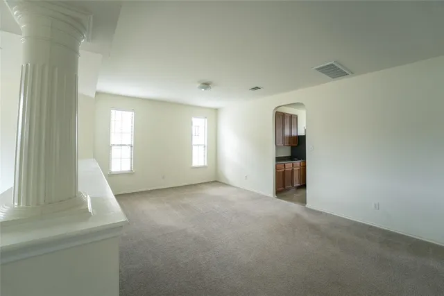 a view of an empty room with wooden floor and stairs