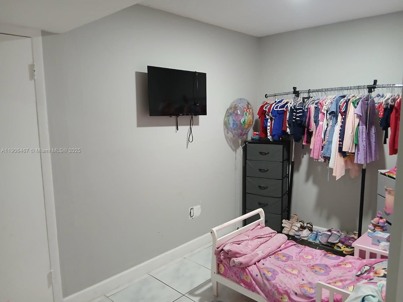 6070 West 19th Avenue, Unit 110 Hialeah, FL 33012 - Photo 6 of 9 a bedroom with a bed and a flat screen tv