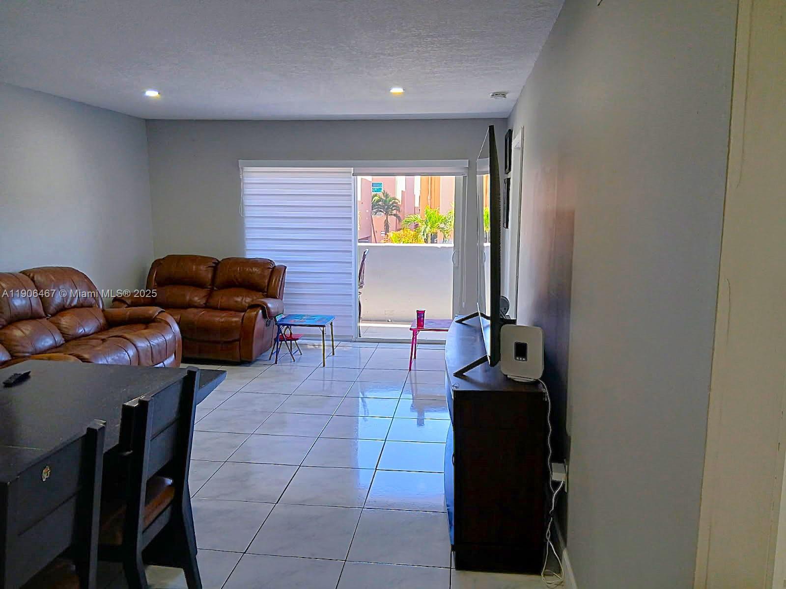 6070 West 19th Avenue, Unit 110 Hialeah, FL 33012 - Photo 8 of 9 a living room with furniture and a flat screen tv
