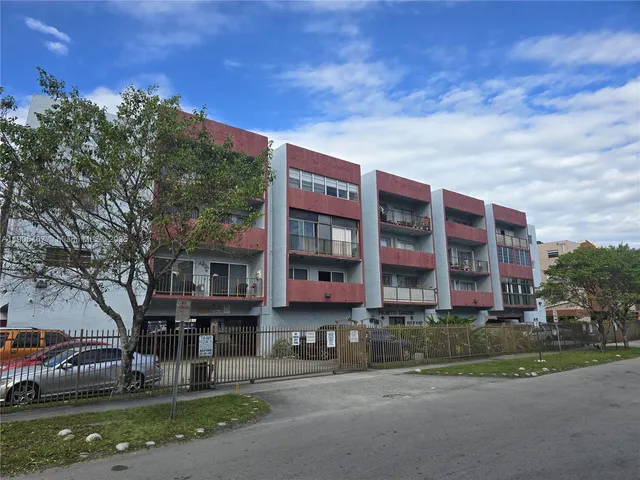 a front view of a building with street view and trees