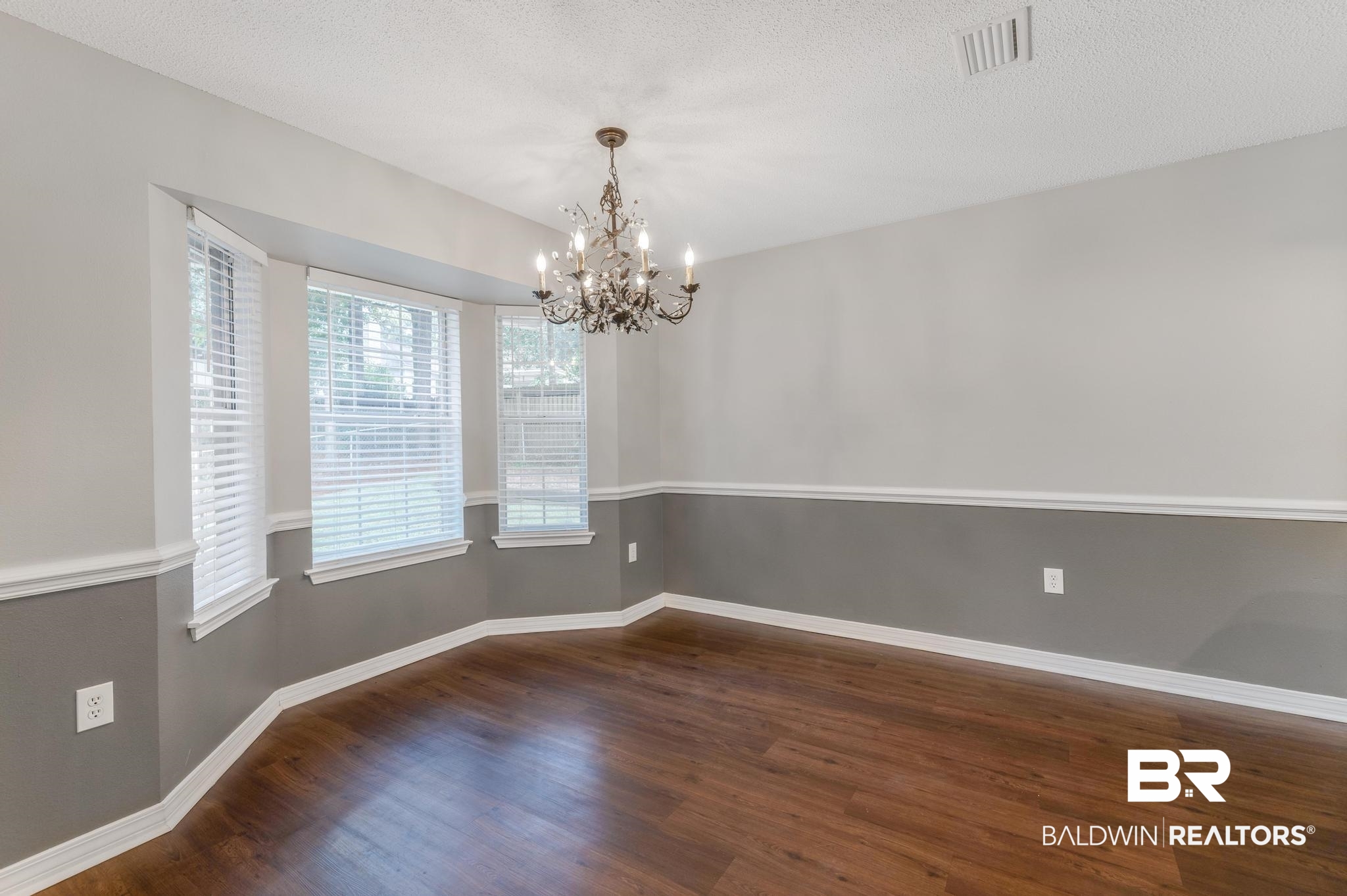 140 Hope Drive Daphne, AL 36526 - Photo 17 of 54 Empty room featuring dark wood finished floors, a textured ceiling, and a chandelier