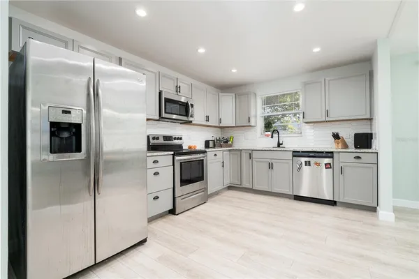 a kitchen with white cabinets stainless steel appliances and a refrigerator