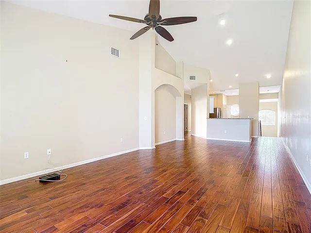 an empty room with wooden floor and ceiling fan