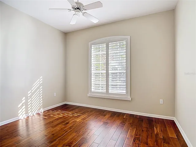 a view of empty room with wooden floor and fan