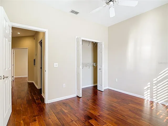 an empty room with wooden floor cabinet and a ceiling fan