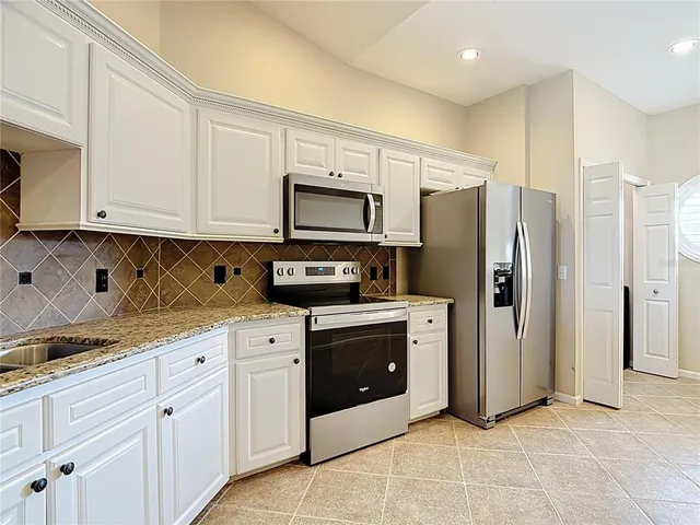 a kitchen with granite countertop white cabinets stainless steel appliances and a counter space