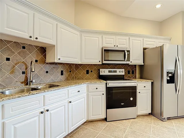 a kitchen with stainless steel appliances granite countertop a refrigerator sink and white cabinets