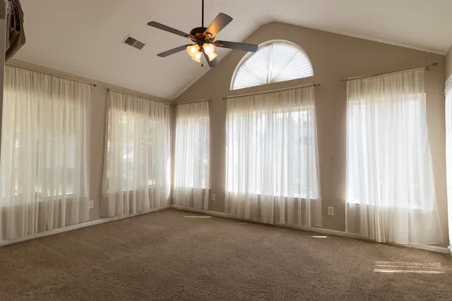an empty room with windows and fan