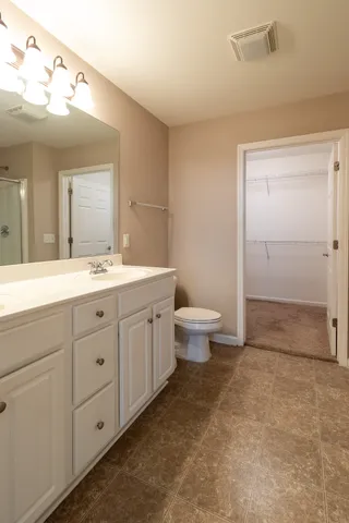 a spacious bathroom with a double vanity sink a toilet and a mirror