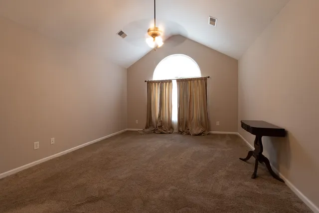 an empty room with windows and fan