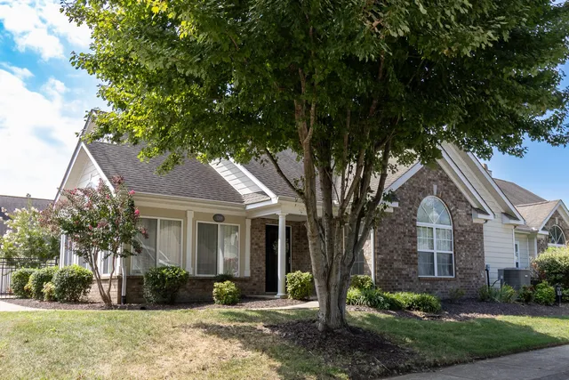 a front view of a house with a yard and potted plants
