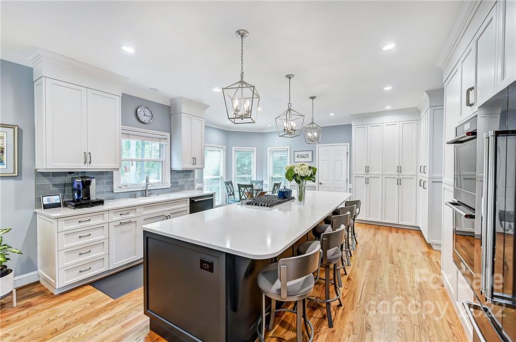 a kitchen with stainless steel appliances a center island wooden floor cabinets and a window