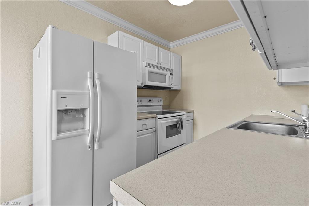 4615 Bayshore Drive, Unit E4 Naples, FL 34112 - Photo 5 of 30 a kitchen with stainless steel appliances a refrigerator stove and microwave