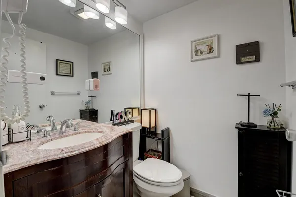 a bathroom with a granite countertop toilet sink and mirror
