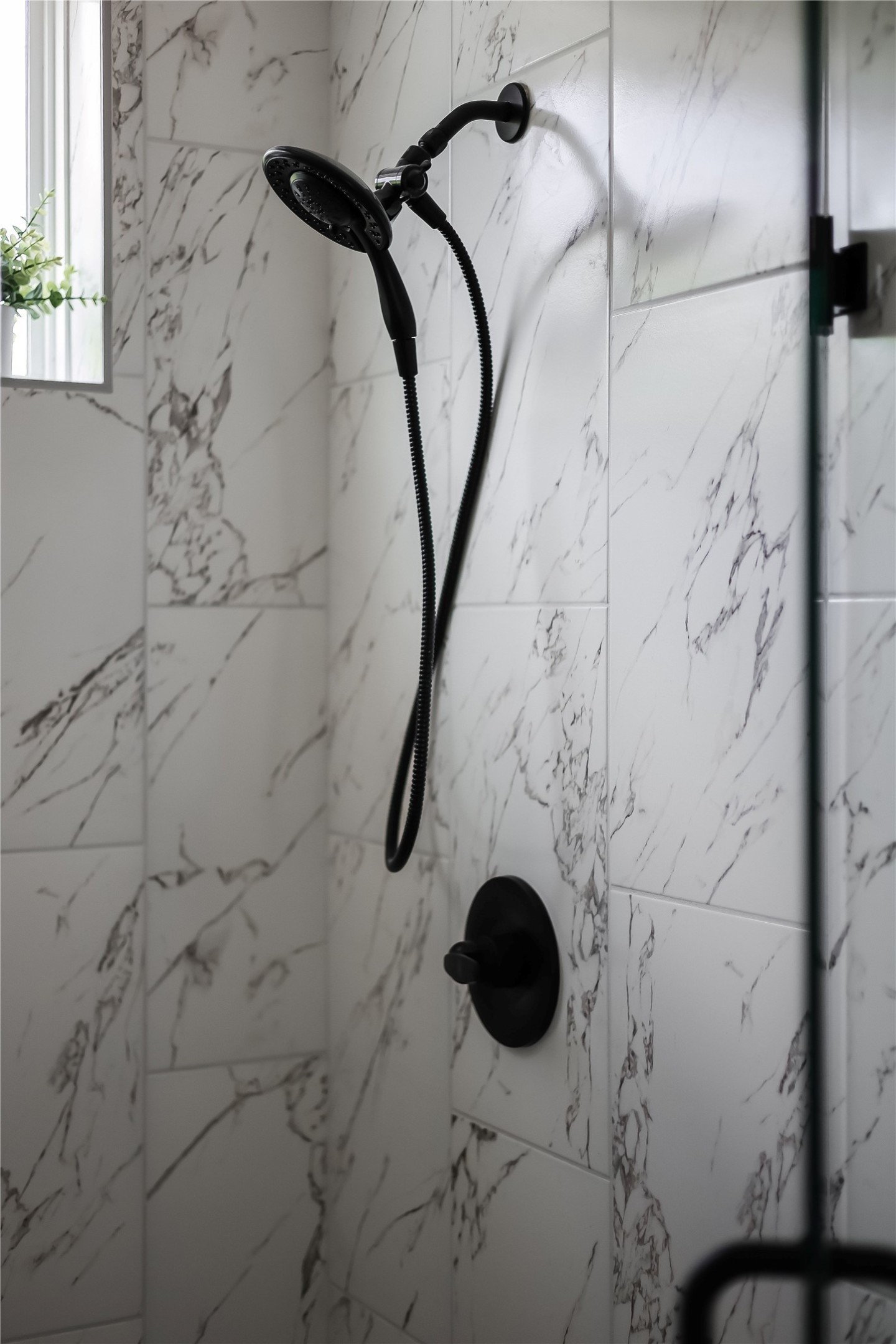 6809 Porter Street, Unit 1 Austin, TX 78741 - Photo 30 of 40 Marble-look tile walls with contrasting matte black shower fixtures create a striking modern aesthetic.