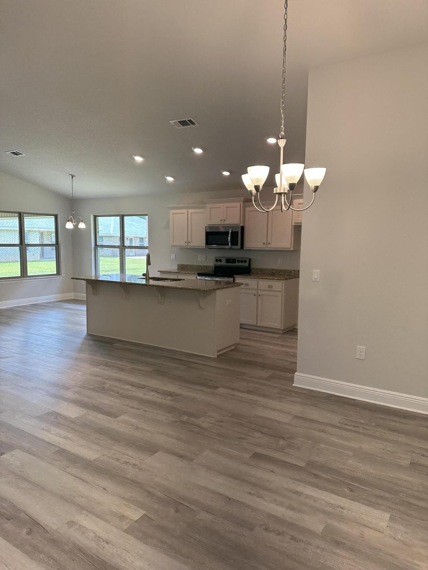 5287 Hidden Pines Circle Milton, FL 32583 - Photo 5 of 15 a view of a kitchen with a dishwasher a kitchen island a chandelier and wooden floor