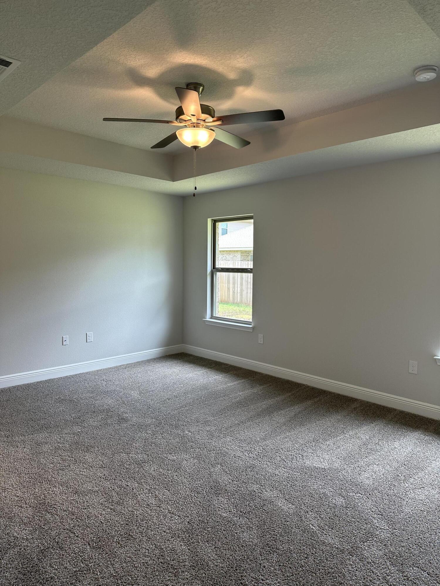 5287 Hidden Pines Circle Milton, FL 32583 - Photo 9 of 15 an empty room with a chandelier fan and windows