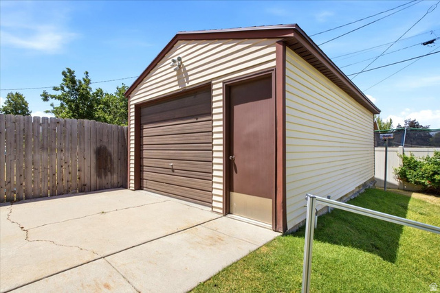 7050 South 260 East Midvale, UT 84047 - Photo 26 of 28 Detached garage featuring horizontal siding, a brown sectional garage door, a side entry door, and a concrete driveway