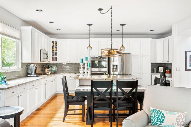 a kitchen with stainless steel appliances kitchen island granite countertop a table chairs and a refrigerator