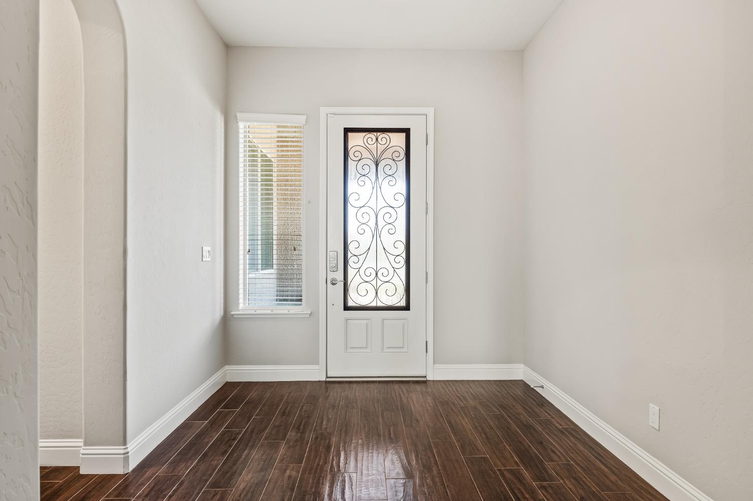 an empty room with wooden floor and window