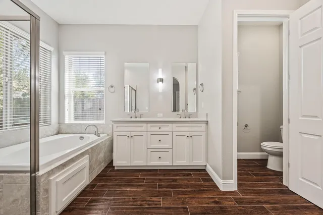 a spacious bathroom with a granite countertop sink a toilet and a bathtub
